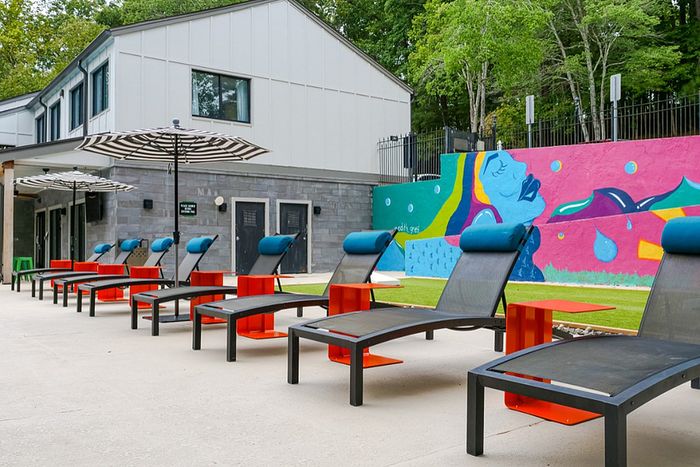 Vibrant apartment outdoor area with stylish lounge chairs, colorful mural, and lush greenery.