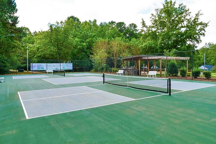 Inviting outdoor tennis courts surrounded by lush greenery, perfect for sports enthusiasts seeking a peaceful setting.