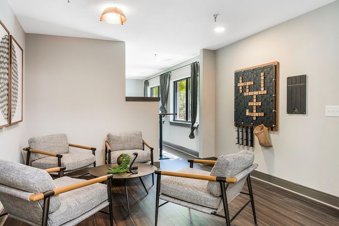 Inviting lounge area in modern apartment with stylish armchairs, a sleek coffee table, and large windows for natural light.