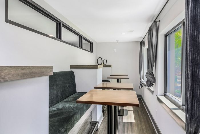 Modern seating area with plush bench, sleek wooden tables, and large windows filling the space with natural light.