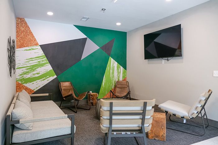 Modern lounge area featuring stylish geometric wall art, comfortable seating, and a sleek mounted TV.