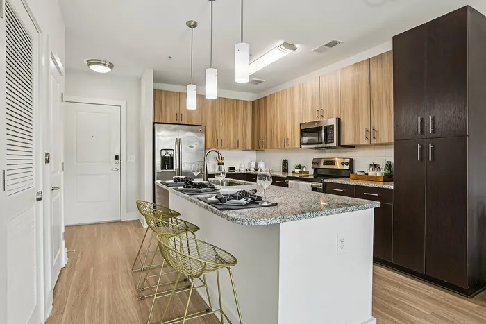 Modern kitchen with elegant granite island, stylish pendant lighting, and sleek stainless steel appliances.