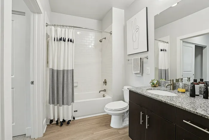 Elegant bathroom with granite countertop, modern fixtures, and cozy bathtub adorned with stylish drapes.