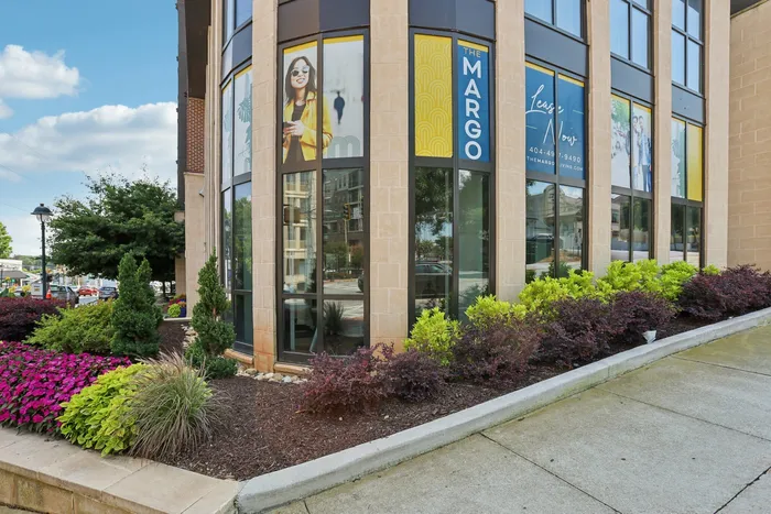 Elegant corner facade of 'The Margo', showcasing modern architecture with large windows, vibrant landscaping, and inviting street views.
