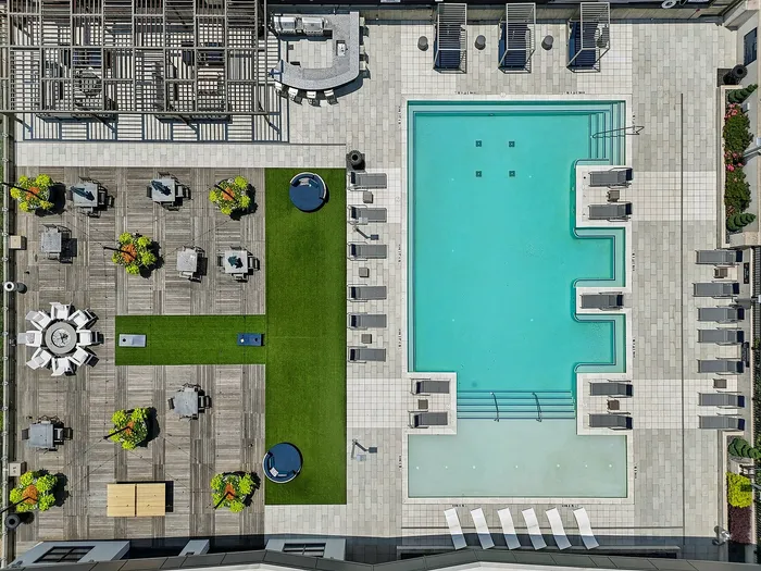 Luxurious aerial view of modern apartment amenities showcasing a sparkling pool, vibrant green spaces, and stylish lounge areas.