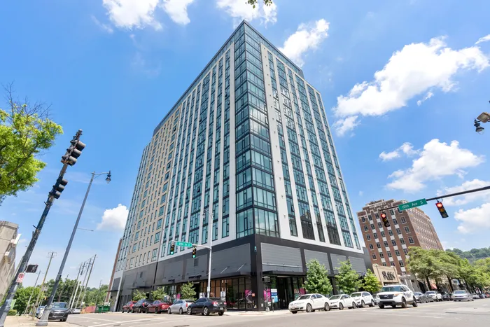 Modern high-rise building with expansive windows under a vibrant blue sky, ideal for upscale urban living.