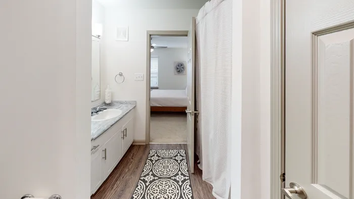 Inviting modern bathroom with elegant vanity, stylish countertop, and a view into a cozy bedroom.