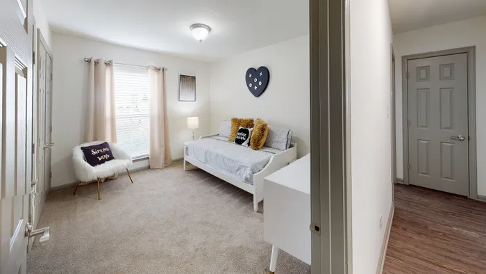 Cozy bedroom with modern decor, featuring a comfortable daybed, plush chair, and soft lighting, exuding warmth and tranquility.