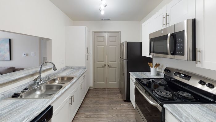 Sleek and modern kitchen with stainless steel appliances, marble countertops, and ample cabinet space.