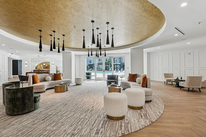 Modern lounge area with chic furniture, plush seating, and stylish lighting, offering a welcoming atmosphere with sunlight streaming through large windows.