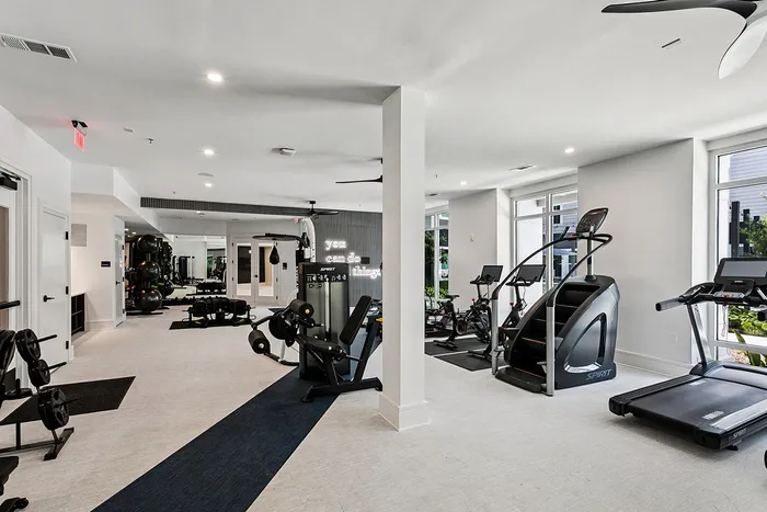 Modern fitness center with state-of-the-art equipment, bright spacious interior, and motivational wall art.