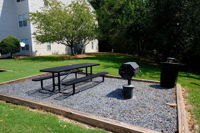 Charming outdoor picnic area with a grill, nestled in a lush green setting, perfect for relaxing and entertaining.