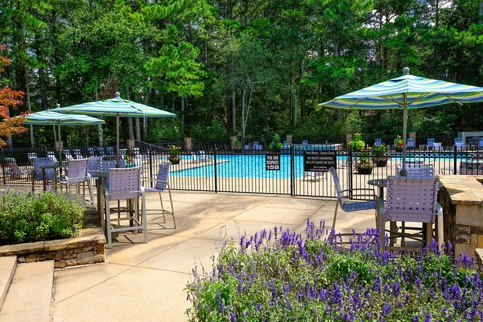 Charming outdoor pool area with stylish seating, vibrant umbrellas, and lush greenery, offering a tranquil retreat for relaxation.