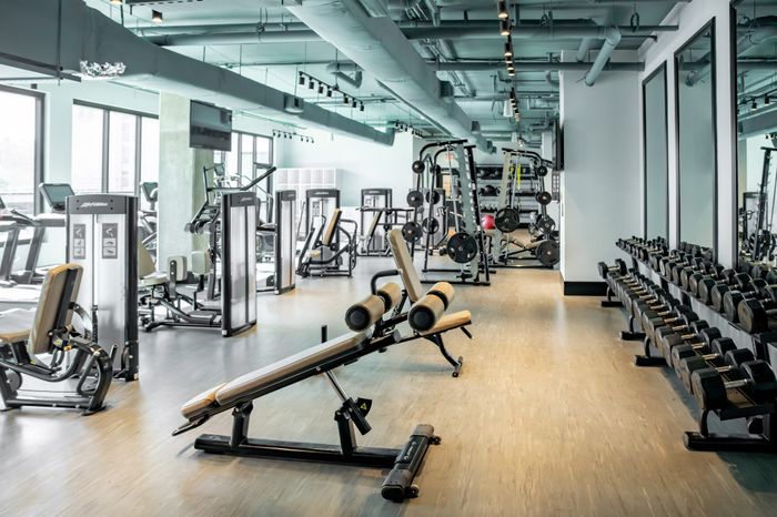 Modern, spacious gym featuring state-of-the-art fitness equipment, bright ambiance, and sleek design for an invigorating workout experience.
