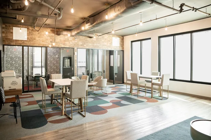 Chic and modern coworking space featuring stylish furniture, vibrant patterned carpet, and ample natural light.