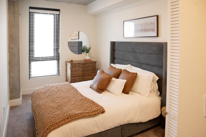 Inviting bedroom with cozy bedding, plush pillows, and stylish decor in a modern apartment.