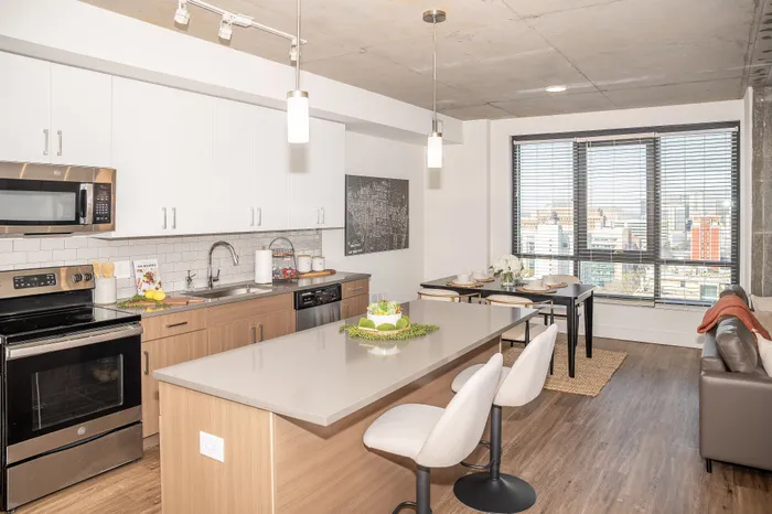 Modern open-concept apartment kitchen with sleek countertops, stylish lighting, and a cozy dining area overlooking cityscape views.