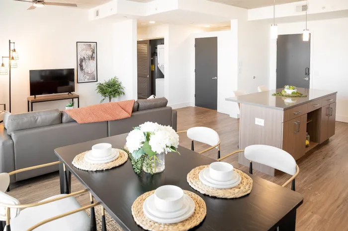 Contemporary open-concept living space with a sleek kitchen island, cozy dining setup, and inviting lounge area, perfect for modern living.