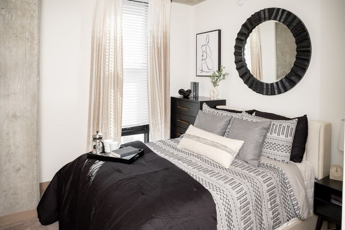 Chic bedroom with stylish decor, featuring modern furnishings, elegant bedding, and a decorative round mirror.