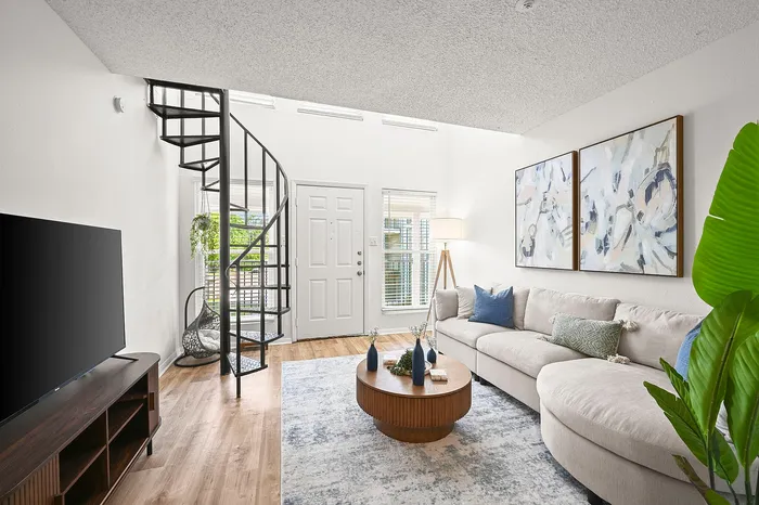 Modern living room with cozy large sofa, elegant spiral staircase, and stylish decor, perfect for relaxing and entertaining.