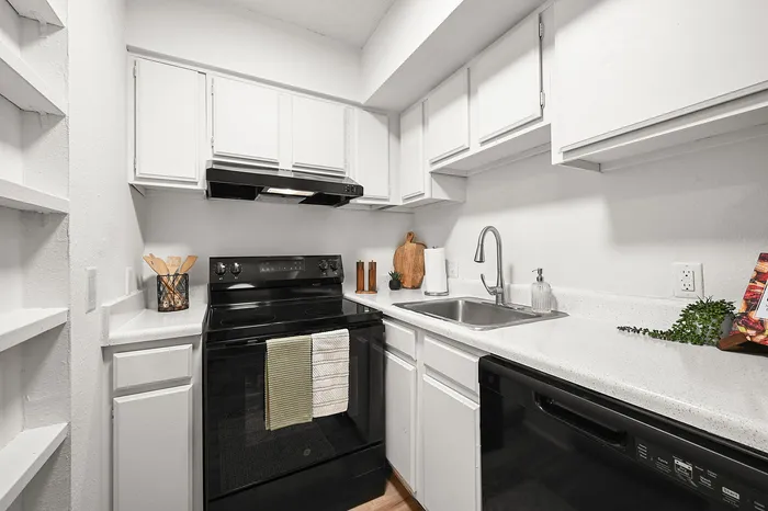 Charming modern kitchen with sleek black appliances, ample white cabinetry, and elegant countertops, perfect for culinary enthusiasts.