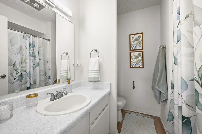 Elegant bathroom with a sleek white countertop, modern fixtures, and botanical-themed decor enhancing its serene ambiance.