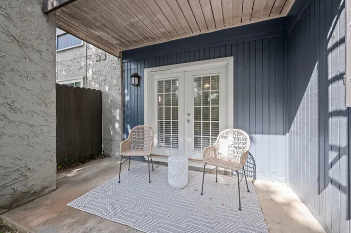 Charming outdoor patio featuring cozy chairs and stylish double French doors, perfect for relaxing and entertaining.