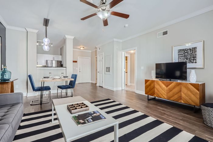 Modern apartment living room with elegant decor, featuring a cozy dining area, sleek hardwood floors, and a stylish ceiling fan.