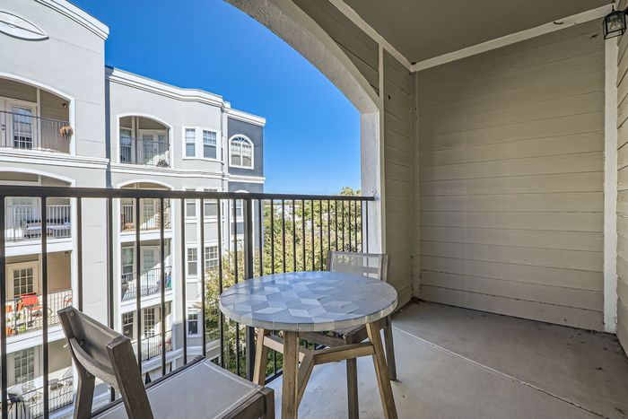 Inviting balcony with modern furniture offering scenic views and a glimpse of elegant neighboring architecture.