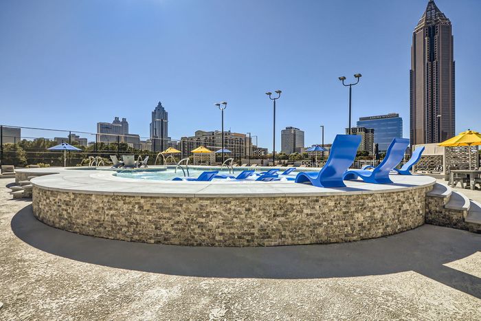 Contemporary rooftop pool with sleek blue loungers, offering stunning skyline views in a vibrant urban setting.