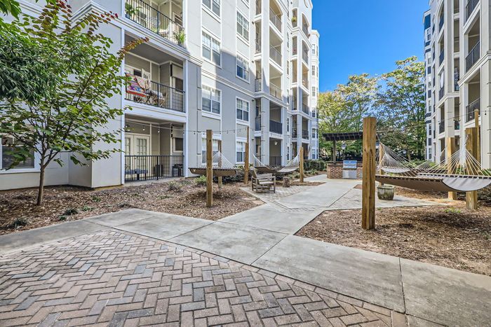 Chic apartment complex exterior with spacious balconies and cozy hammocks in the courtyard, perfect for relaxation and outdoor living.