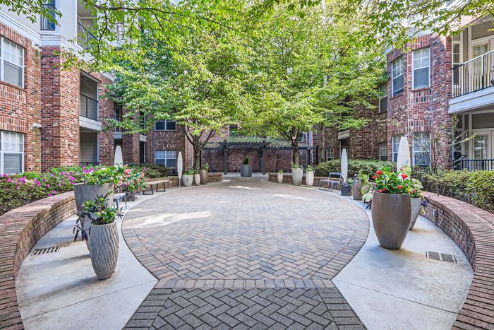 Charming brick courtyard surrounded by greenery, featuring elegant planters and inviting seating areas.