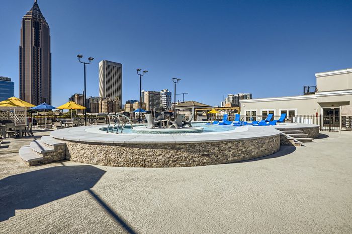 Urban oasis with a luxurious rooftop pool and stunning city skyline views, surrounded by vibrant blue loungers and vibrant umbrellas.