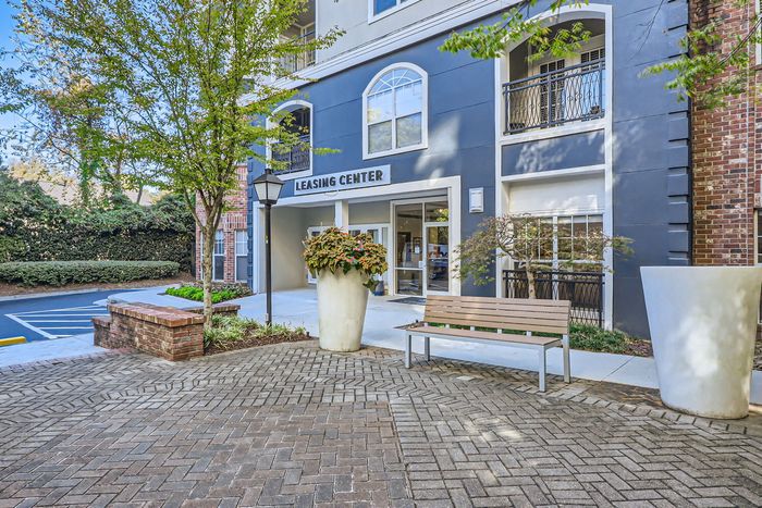 Inviting apartment leasing center with elegant landscaping, welcoming benches, and a charming architectural facade.