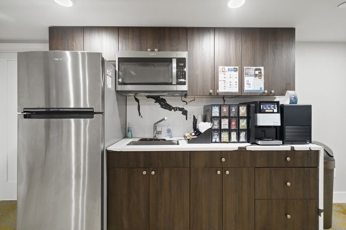 Sleek kitchen area with stainless steel fridge, microwave, and coffee station.