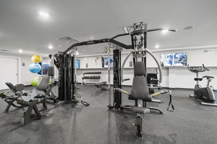 Modern workout room with various gym equipment including a weight rack and exercise bikes.