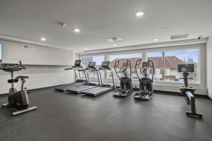 Spacious fitness center with modern gym equipment and large windows.
