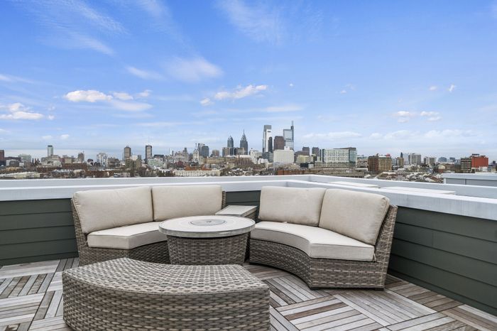 Rooftop terrace with modern seating offering a panoramic city skyline view under a clear blue sky.