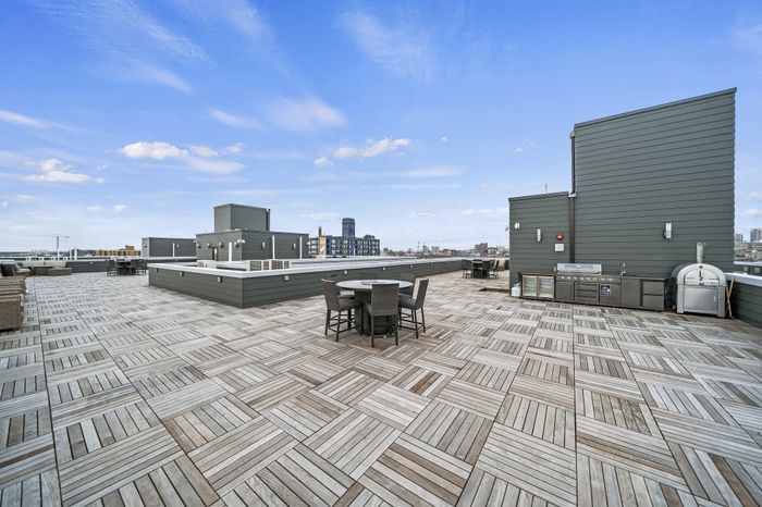 Spacious rooftop terrace with modern seating and outdoor kitchen featuring city skyline views.