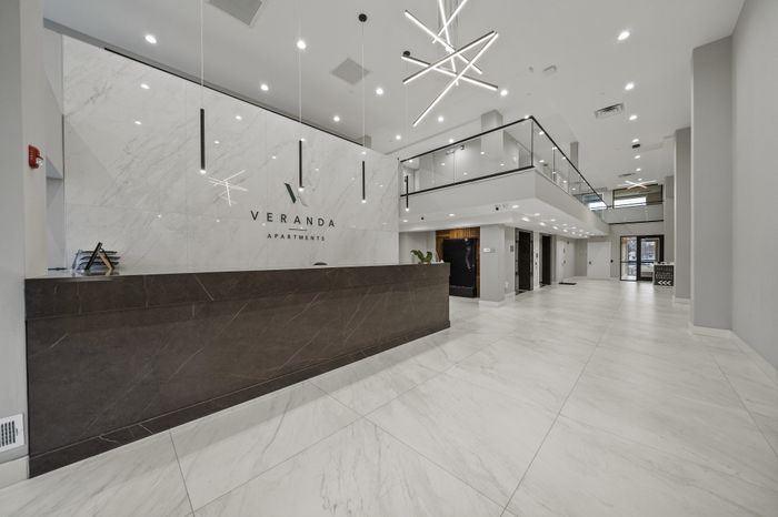 Luxurious lobby space at Veranda Apartments featuring modern design with a sleek reception desk and impressive lighting fixtures.