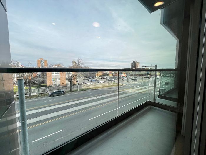 Scenic urban vista from a glass balcony with distant city buildings and a road view.