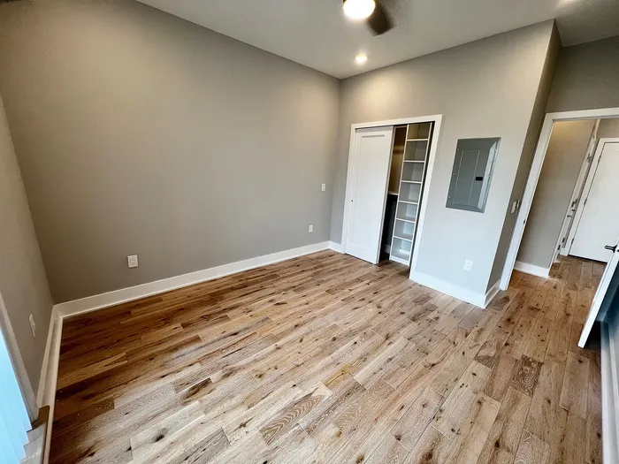 Spacious bedroom with wooden flooring and built-in closet.
