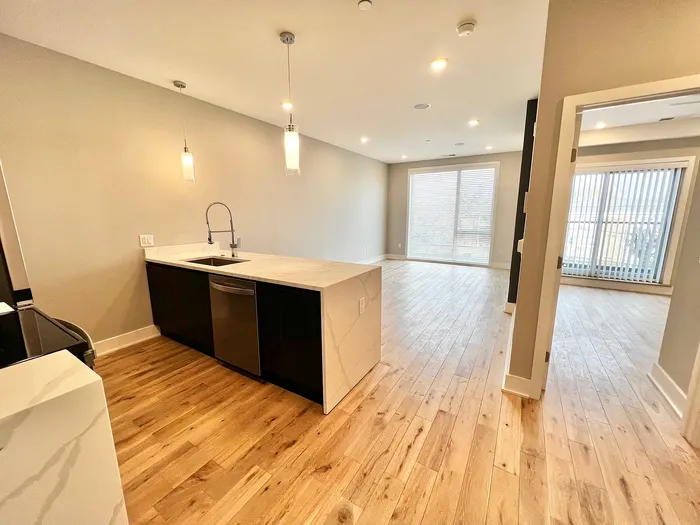 Contemporary open-concept kitchen and living area featuring sleek hardwood floors and modern lighting.