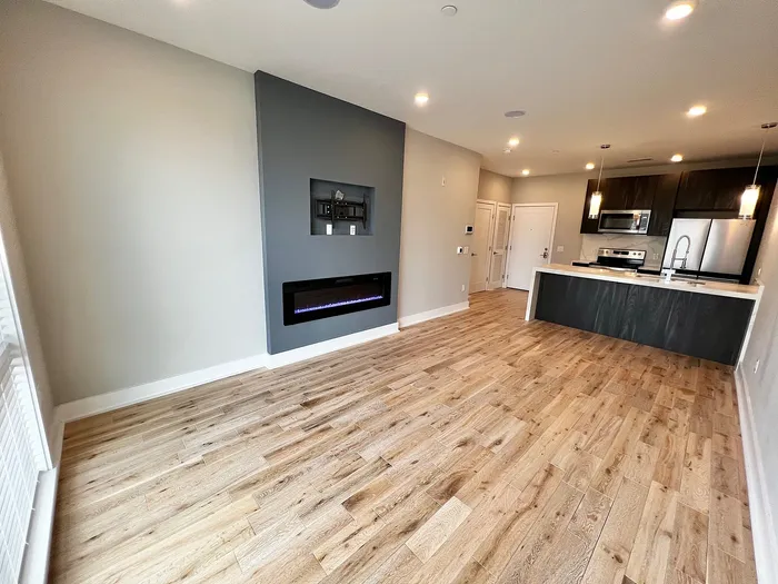Bright open-concept area with hardwood floors, a sleek modern kitchen, and a stylish electric fireplace.