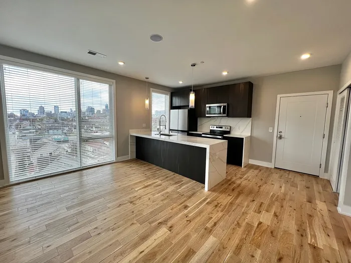 Bright and modern apartment kitchen with hardwood floors, island, and city view.