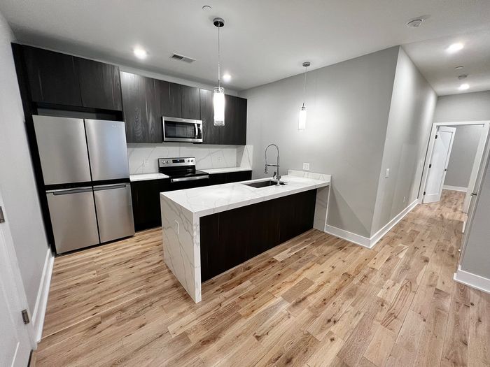 Contemporary kitchen with stainless steel appliances, dark wood cabinets, and marble countertops.