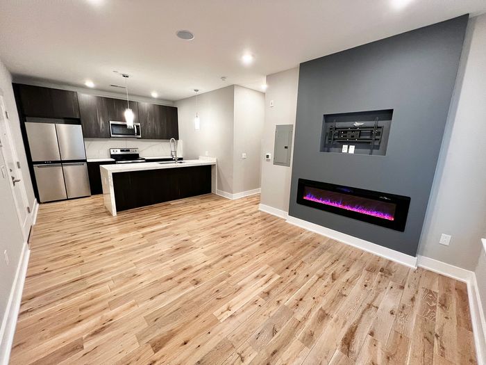 Sleek modern kitchen with stainless steel appliances and an elegant linear fireplace in a bright open-concept layout.