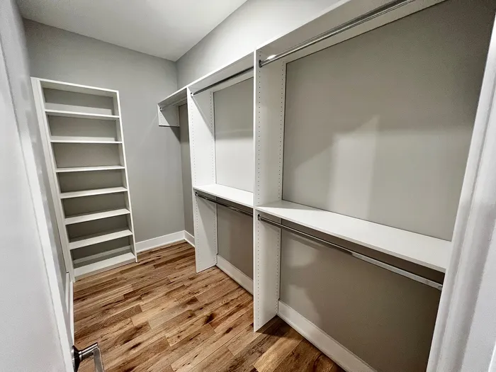 Spacious walk-in closet with modern shelving and sleek hardwood floors.