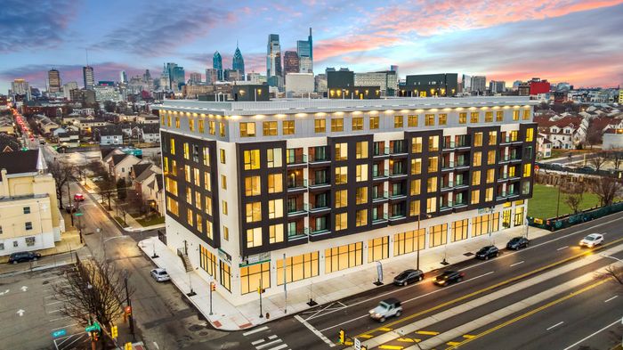 Modern multi-story apartment building in vibrant cityscape at sunset.