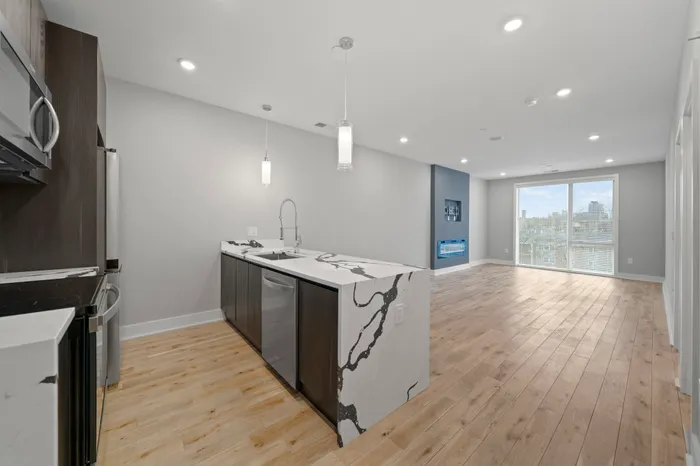 Bright open-plan kitchen and living room with modern appliances and wood flooring.
